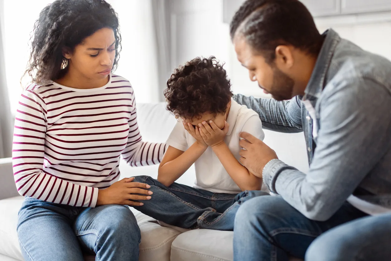 Parents comforting their child together on a sofa